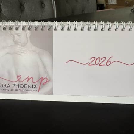 Front of a desk calendar, showing a black and white picture of two men embracing and the text "Nora Phoenix - 2026".